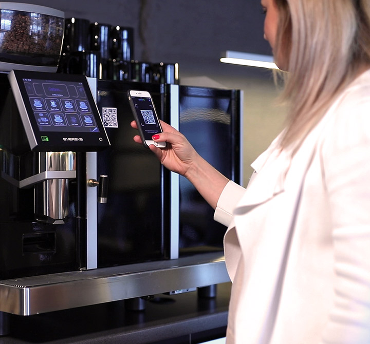Woman scanning QR code at coffee machine.